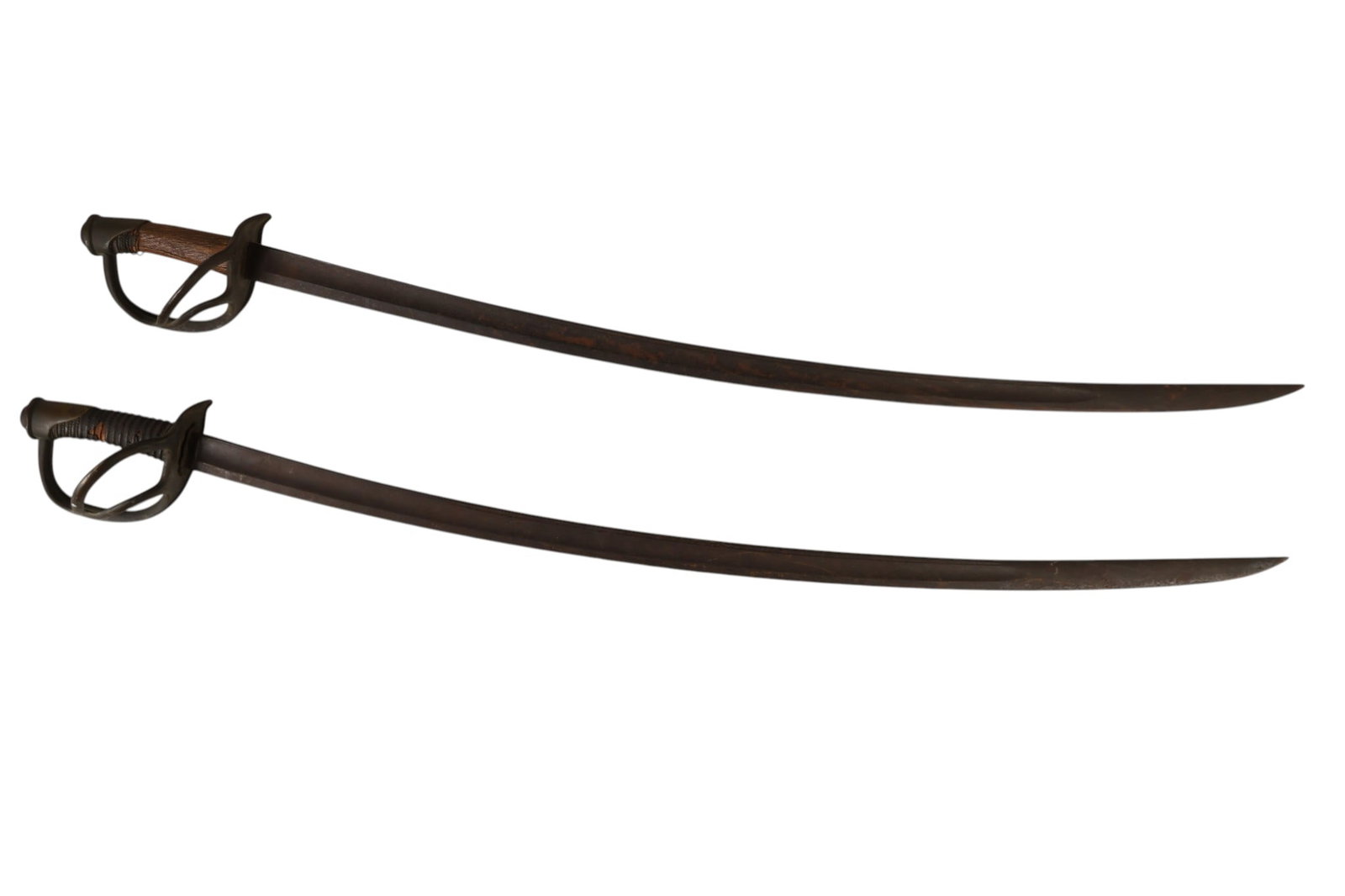 Civil War Era Pr Cavalry Saber Edged Weapon Swords: Lot of two estate swords each modeled with curved steel blades and three branch metal guards featuring knuckle bows and pommel caps. Both examples retain wood grips, one wrapped in leather with wire b