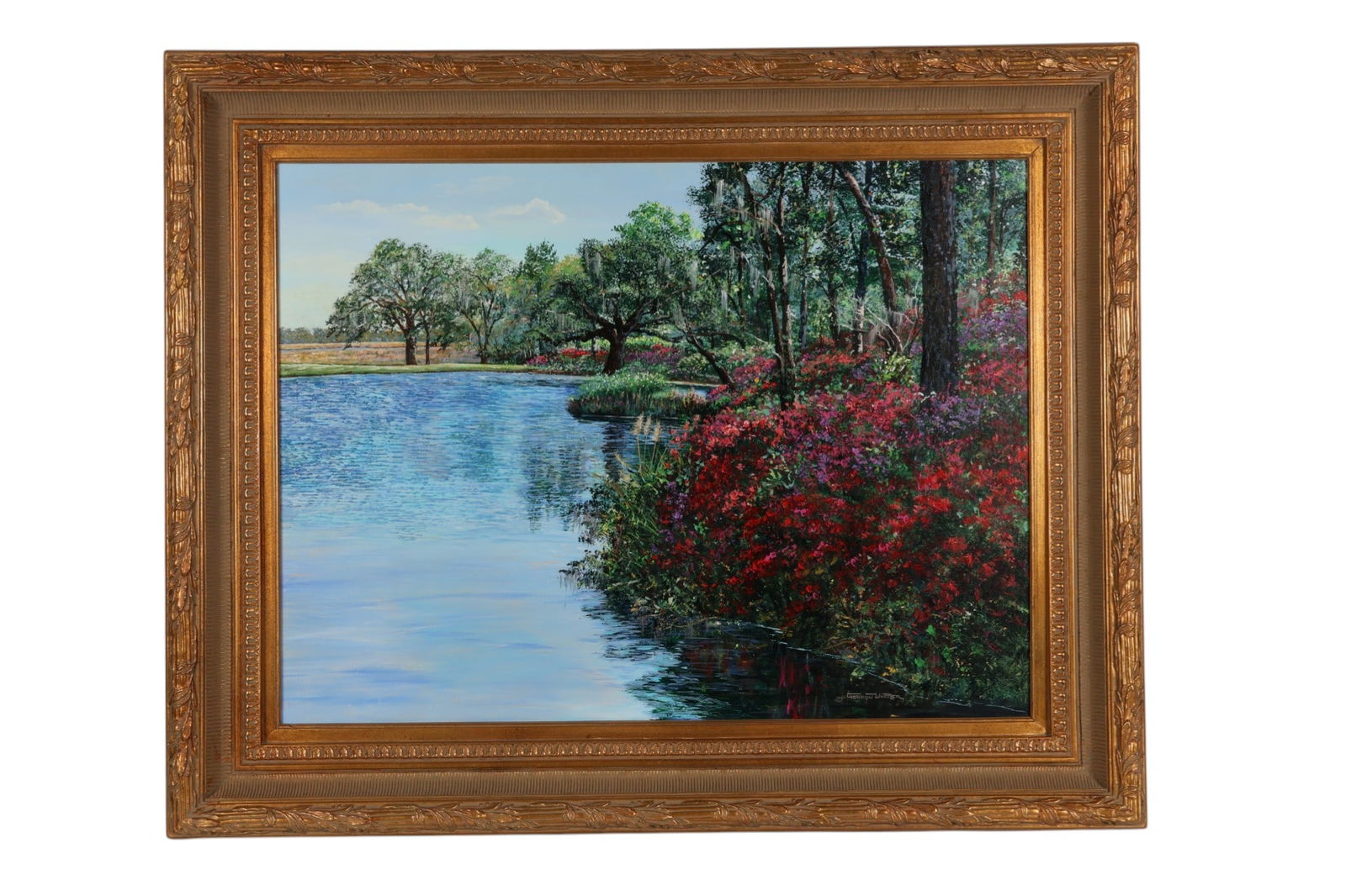 Gordon Wheeler 20C Lakeside Landscape Painting: Gordon Wheeler (American, 20th century), an oil on canvas depicting a serene lakeside landscape with flowering shrubs in bloom along the shoreline, mature trees draped with moss, and calm reflective w