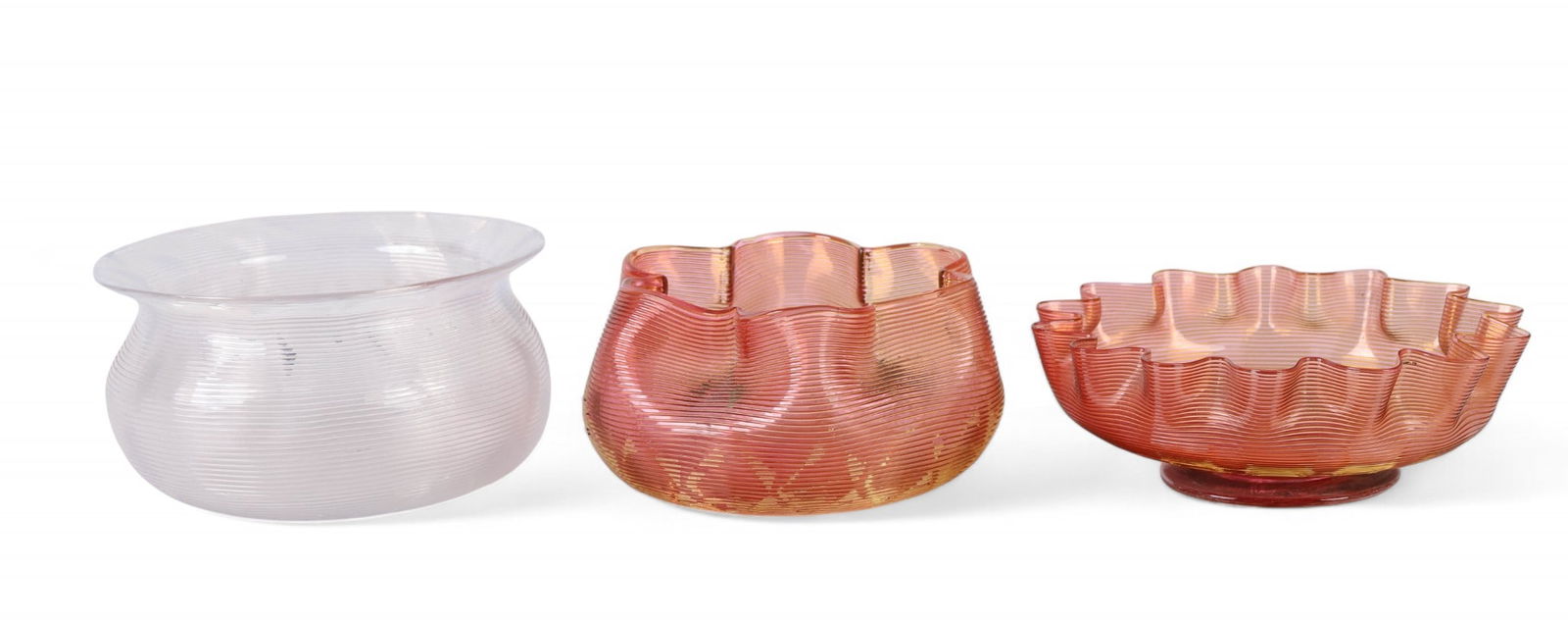Steven Williams Antique Art Glass Ribbed Bowls LOT: Stevens and Williams antique hand blown English studio art glass bowls, lot of three. Includes one with a wide flared rim in clear glass and two amber peach-toned examples with ruffled edges, one feat