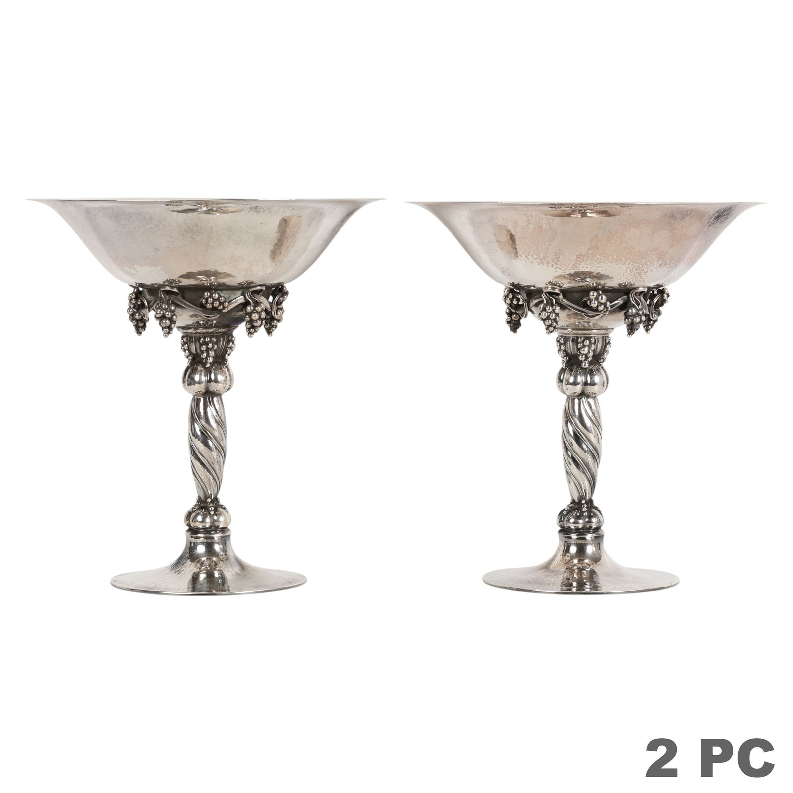 Georg Jensen Pair of Sterling Grape Tazze 2,270g: Georg Jensen, a pair of sterling silver tazza form compotes in the iconic Grapes pattern, each featuring a semi hammered bowl supported by a twisted stem richly adorned with sculpted grape and leaf cl