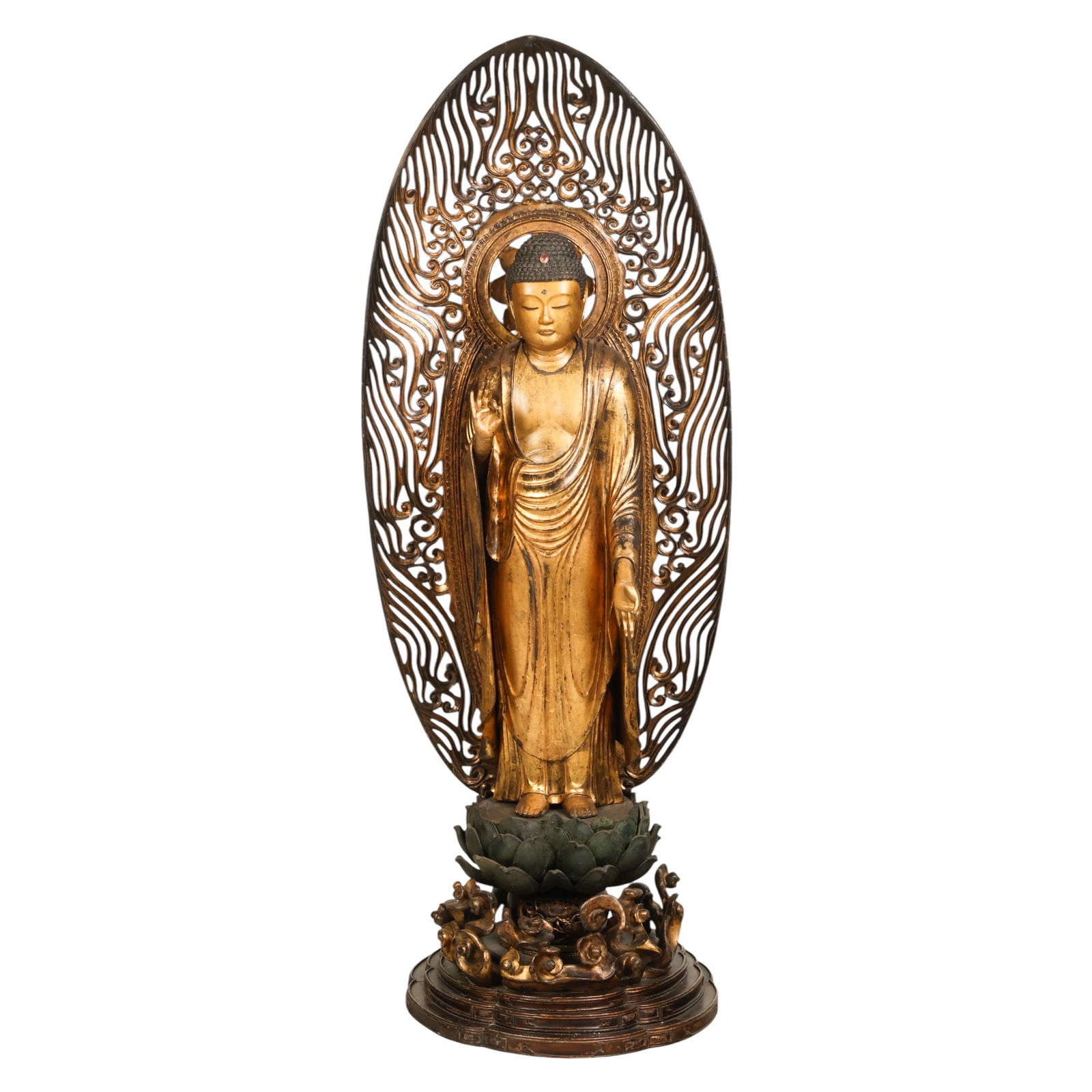 Japanese Antique Giltwood Amida Buddha Sculpture: Japanese, an antique giltwood Buddha figure depicting Amida standing upon a lotus pedestal set over a cloud form base and framed by an openwork flaming mandorla. The figure is rendered with hands
