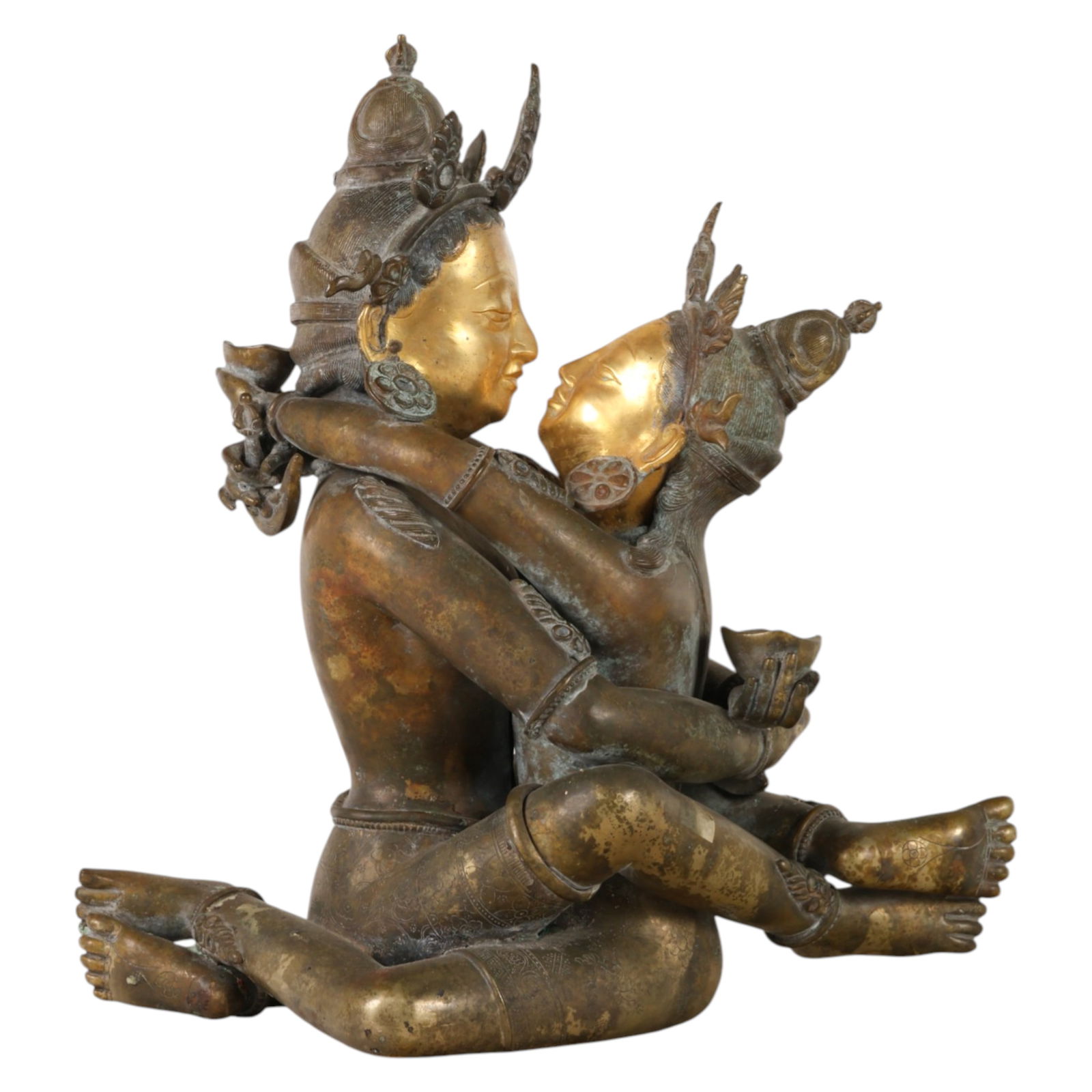 Tibetan Gilt Bronze Vajrasattva Yab-Yum Sculpture: Tibetan, a bronze statue depicting a tantric Yab Yum figure in seated embrace, the male deity shown in lotus position holding ritual objects while the female consort is entwined around him in symbolic