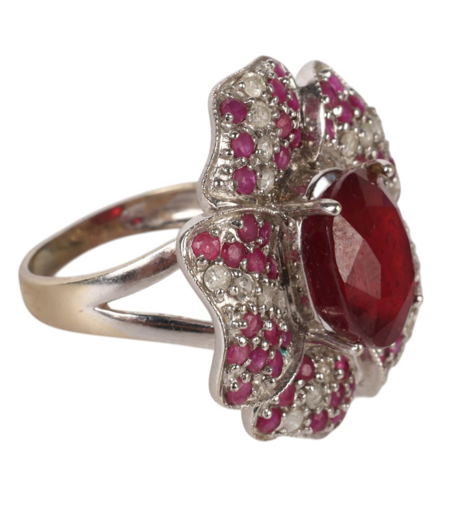 14k White Gold Ruby and Diamond Flower Ring 9.9g.: 14k white gold ruby and diamond ring designed in a floral motif. The ring features a large central oval-cut ruby measuring approximately 11 x 11 mm, estimated at approximately 7 carats, surrounded by