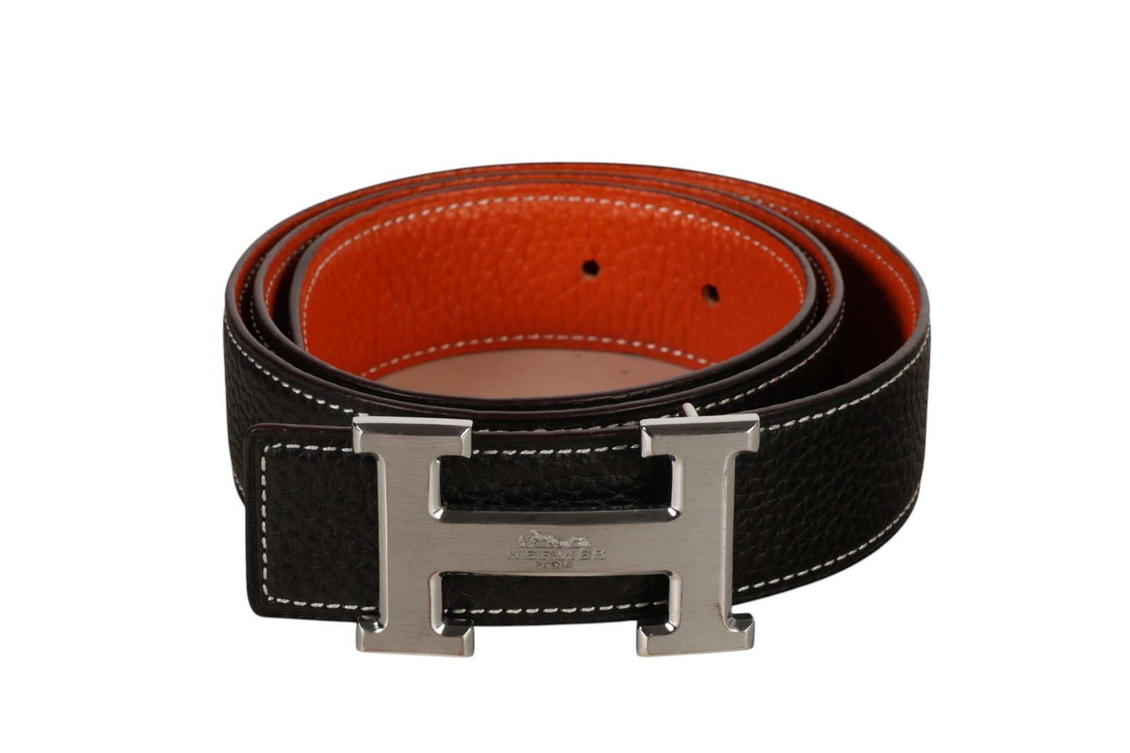 Hermes Reversible Calfskin Leather Strap H Belt: Hermes reversible calfskin leather belt featuring the houses signature H form buckle in chromed metal. The interchangeable strap presents two color options with white contrast stitching, one side in c