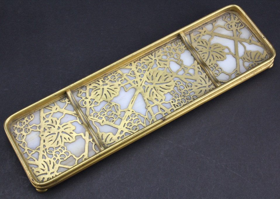 TIFFANY STUDIO Grape Vine Glass Desk Pen Rest Tray: Signed TIFFANY STUDIOS Desk Pen Tray Accessory. Wonderful dore gold gilt bronze "Grape Vine" pattern with Caramel slag or favrille glass. Signed TIFFANY STUDIOS NEW YORK 1004 Measures 9 5/8" x 2 7/8" 