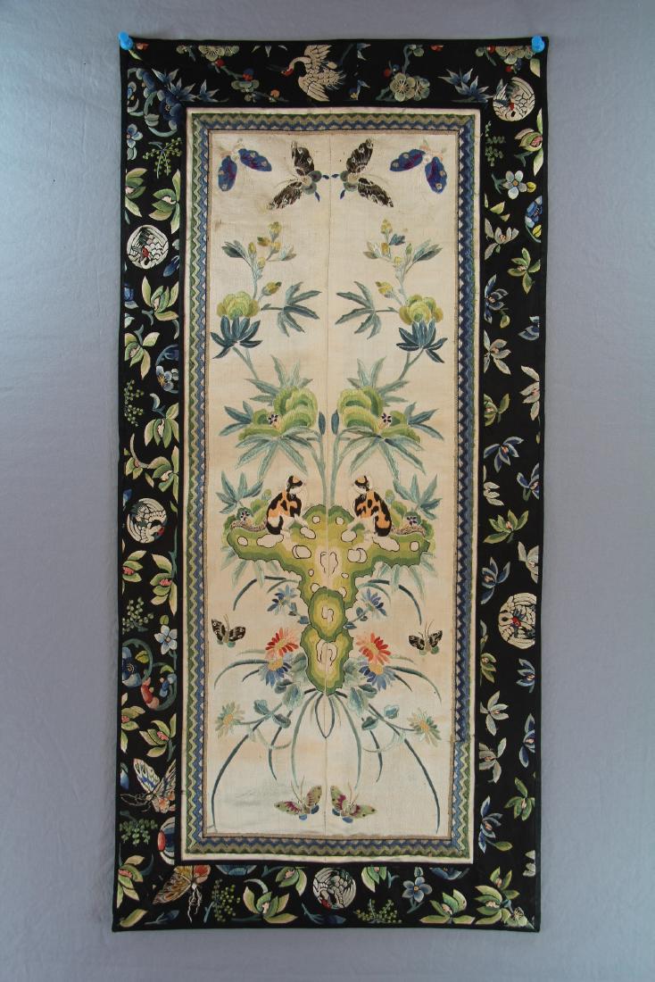 A CHINESE EMBROIDERED SILK PANEL: Stitched together from a pair of sleeve bands, decorated with a lively garden scene of cats on rockworks, butterflies, and colorful flowers, border band embroidered with cranes, butterflies, and flowe