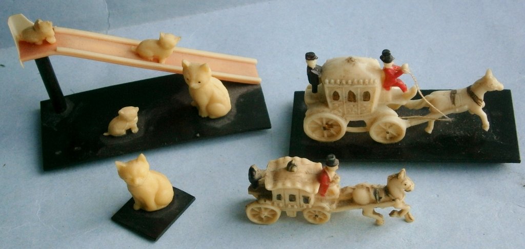 Grouping of 1930s celluloid figurines: Grouping of 1930s celluloid figurines, cat slide is 2 7/8 in. long, coach is 2 5/8 in. long, slide is missing ladder and small coach has damage to head of back coachman.
