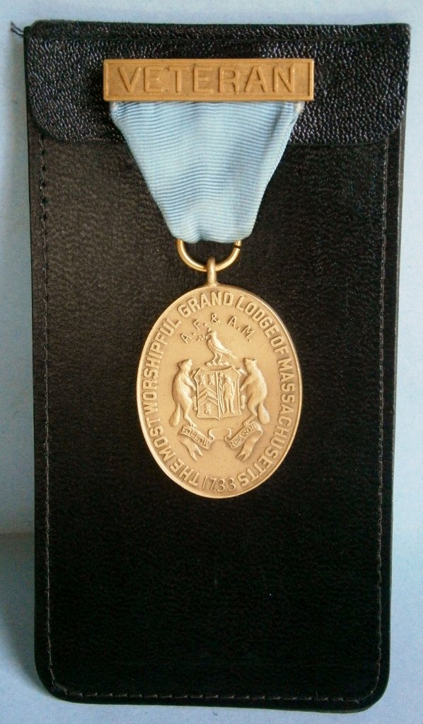 Grand Lodge of Massachusetts 50 Year Service Medal: Grand Lodge of Massachusetts 50 Year Service Medal, 3 1/4 in. tall (medal is 1 5/8 long excluding ring), mounted on leather holder, engraved to recipient on back, made of cast brass.