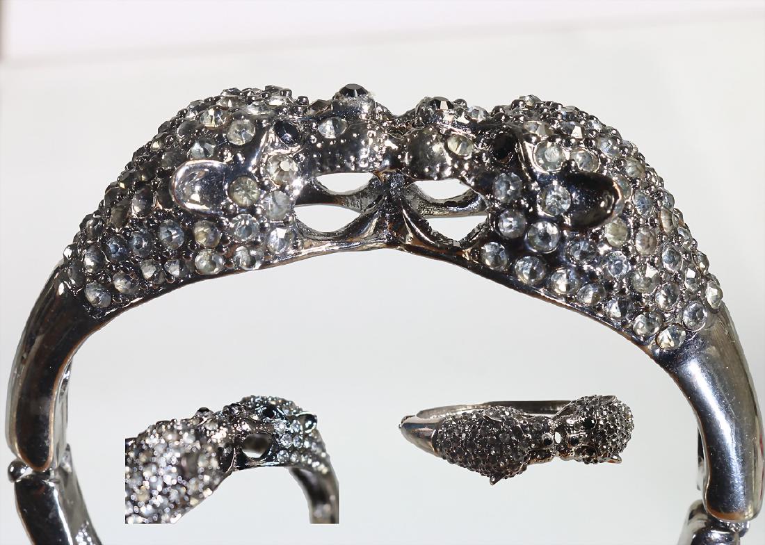 Altsilberfarbene Armspange (unsigniert), zwei: Altsilberfarbene Armspange (unsigniert), zwei Pantherköpfe mit Strassbesatz in weiß u. schwarz, Kastenschloss mit Scharnierbewegung, innen: ca. 62,0 x 53,0 mm