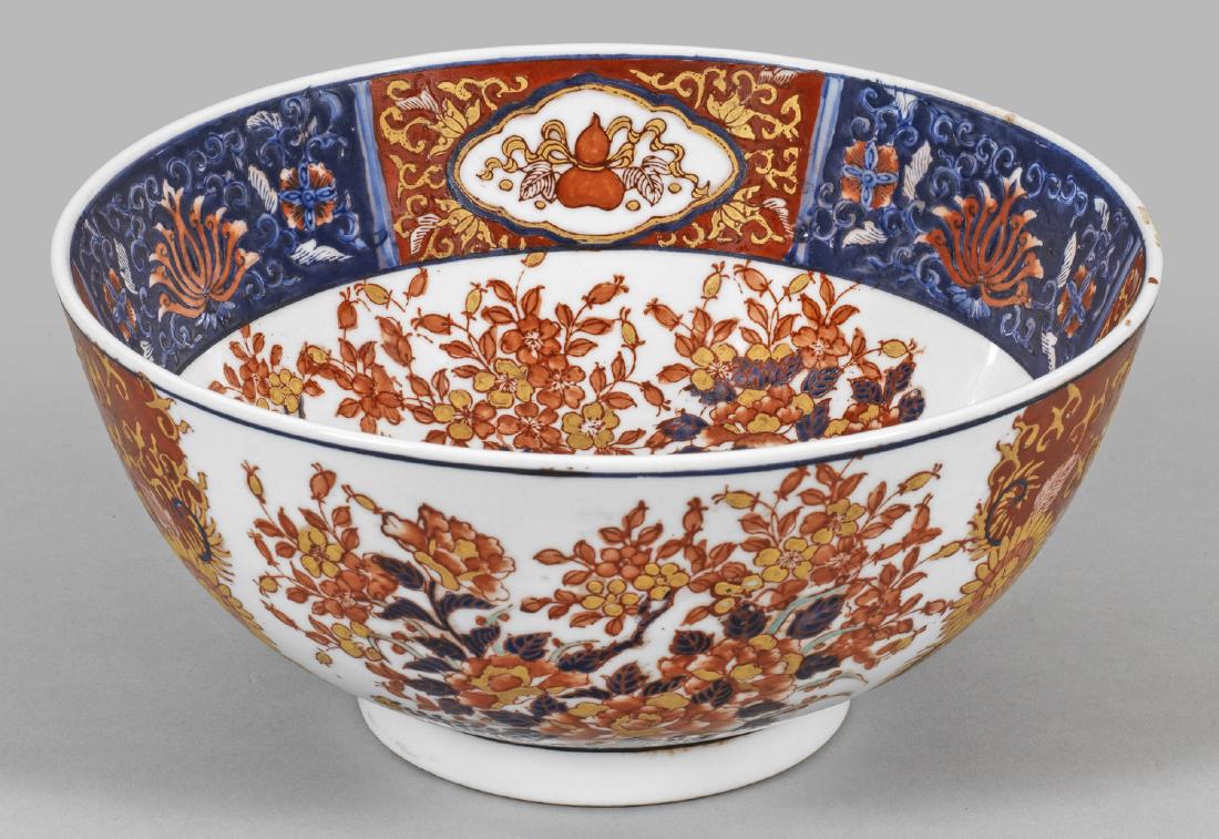 Große chinesische Schale im Imari-Stil: Porzellan. Allseitig flächendeckender Dekor aus großen Buketts mit Chrysanthemen- und Prunuszweigen in polychromer Emailmalerei, Gold gehöht. Breite Bordüre mit Lotus und buddhisti