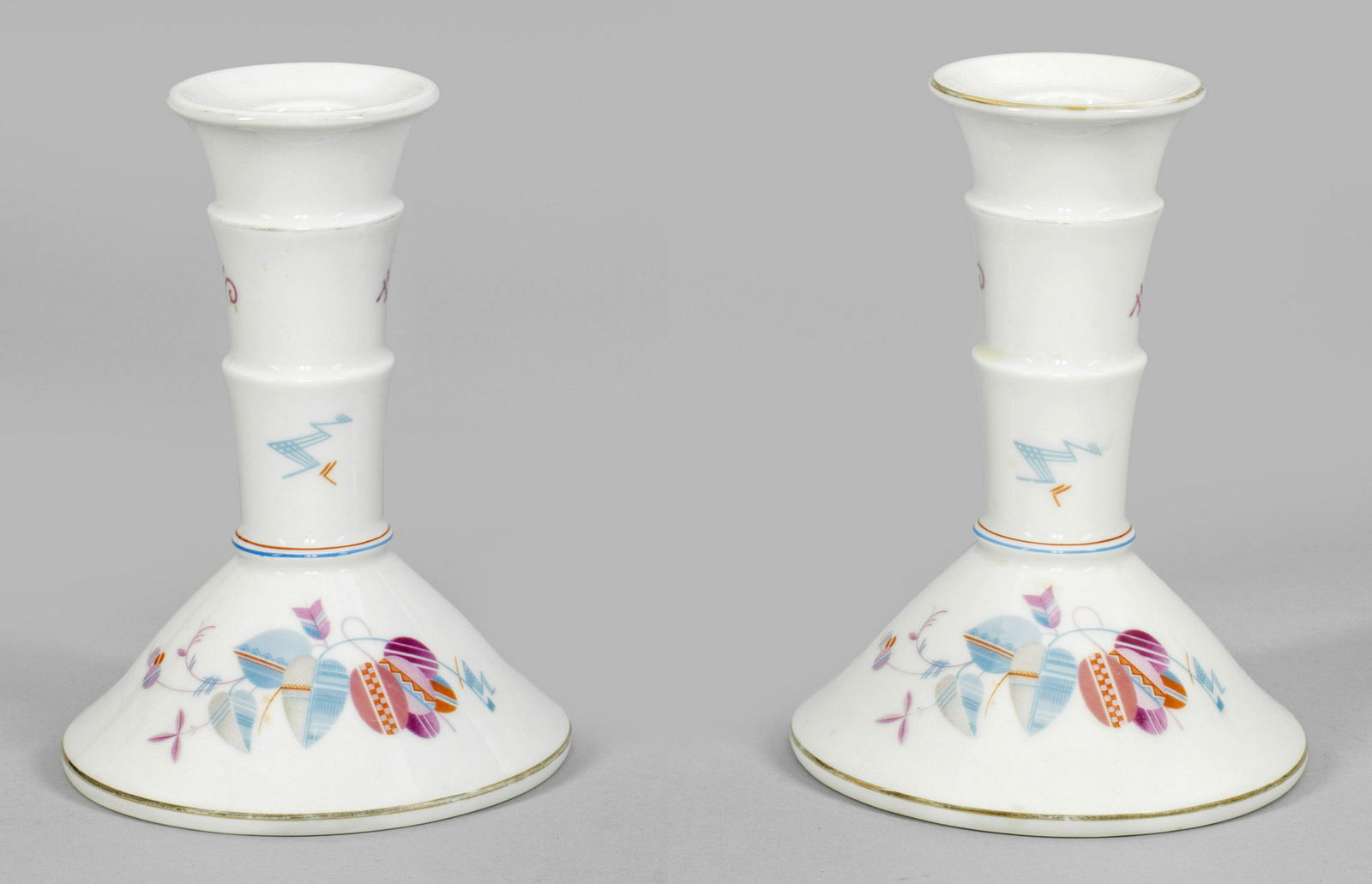 Paar Kerzenleuchter aus dem Service "Madeleine": Sich stufenartig erweiternder Schaft über hochgewölbtem Rundfuß. Umlaufend abstrakter, polychromer Dekor. Goldrand. Form-Entw. Friedrich Fleischmann, 1927. Manufakturmarke. H. 16 cm. A pair of porc
