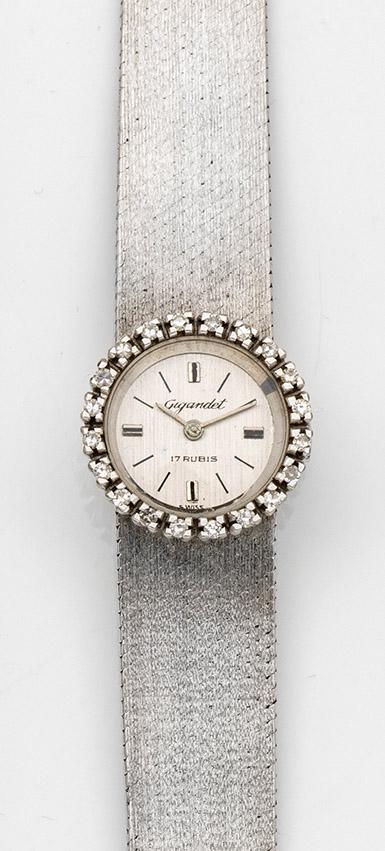 Damenarmbanduhr von Gugandet aus den 70er Jahren: Weißgold, gest. 750. Runders Uhrengehäuse, Lunette besetzt mit Brillanten von zus. ca. 0,38 ct., Zifferblatt mit Stabindexen und Zeigern. Leicht verlaufendes satiniertes Armband mit Faltschl