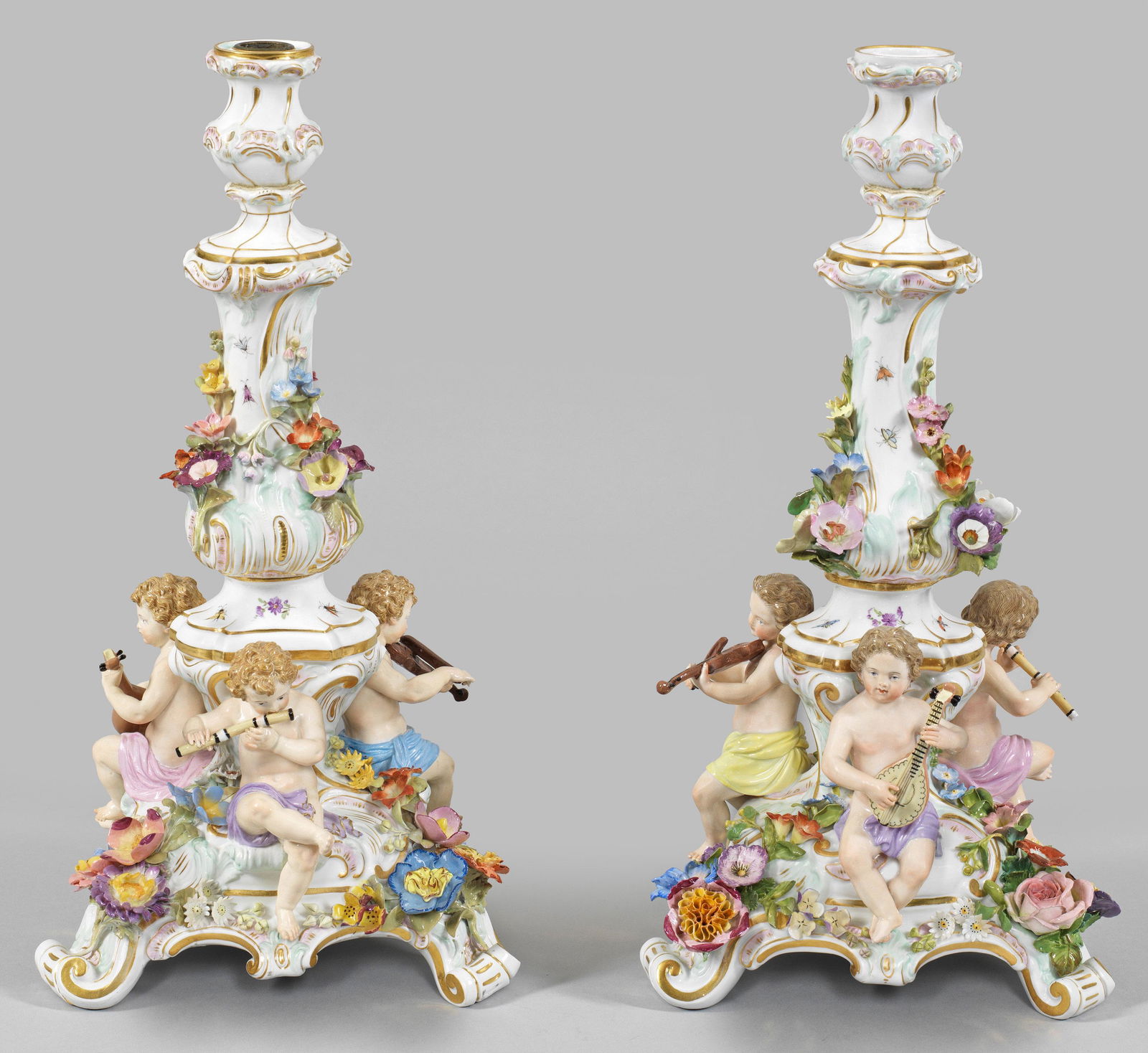 Paar Figurenleuchter: 1-flg.; Von Voluten getragener, dreiseitig geschweifter Sockel, in Balusterschaft mit vasenförmiger Tülle übergehend. Unterhalb sitzende, musizierende Putten mit Laute, Violine bzw. Que
