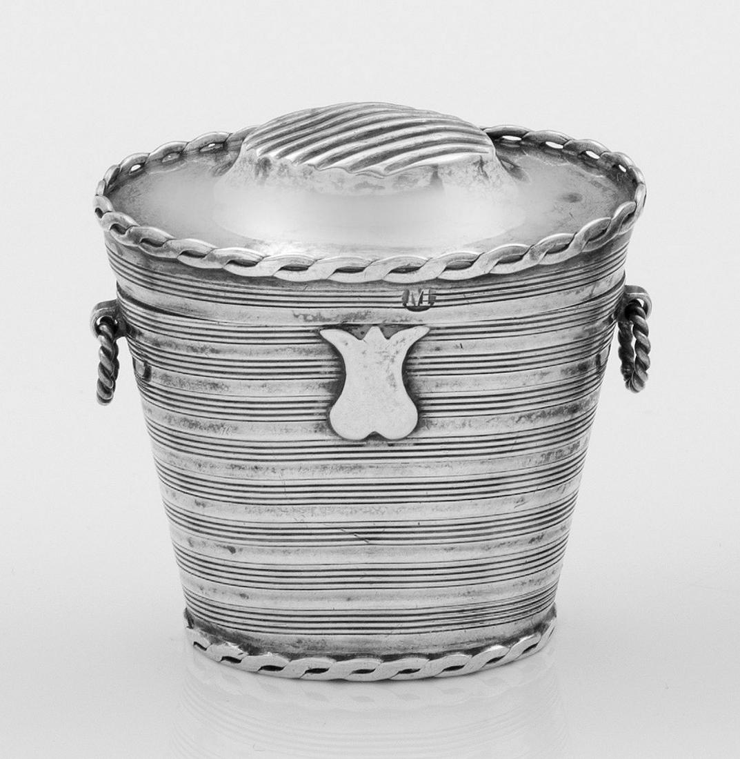 Streichholzbehälter: Silber. Über ovalem Stand sich konisch erweiternder Korpus in der Art eines Korbes mit seitlichen Griffen. Auf dem Deckel Rillen zum Abstreichen eines Zündholzes. Gest., Beschaumarke, Jahres