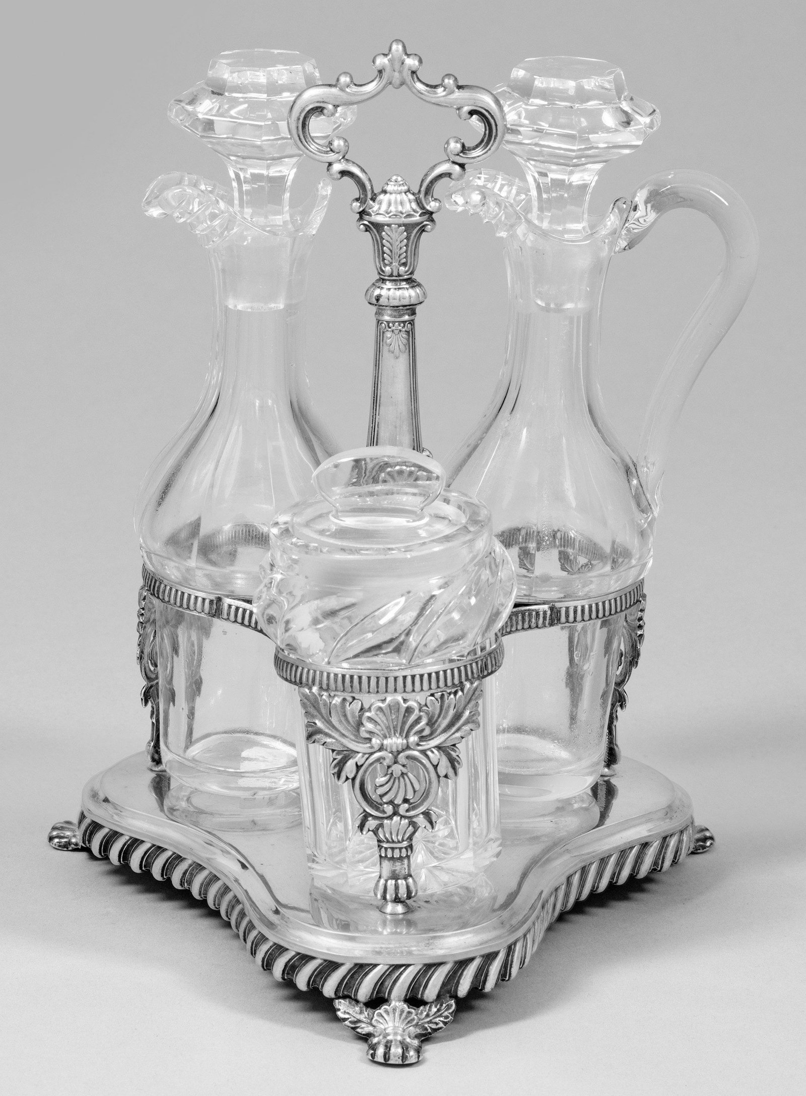 Biedermeier-Menage: Silber. Dreipassiger, von Klauenfüßen getragener Stand. Oberhalb, von blattreliefierten Füßen getragene, kannelierte Halterung für drei Gewürzflaschen. Mittig aufsteigend
