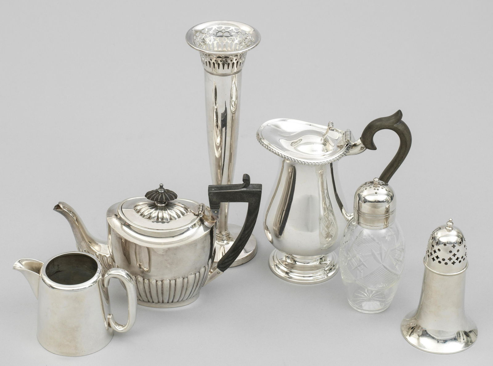 Konvolut Tischaccessoires: Plated. 6-tlg.; Kleine Schenkkanne, Sahnegießer, Orchideenvase, Teekanne und 2 Zuckerstreuer, teilw. aus Kristallglas. Telw. gem. Five plated table accessories. Partly marked. England. 19./20. Jh