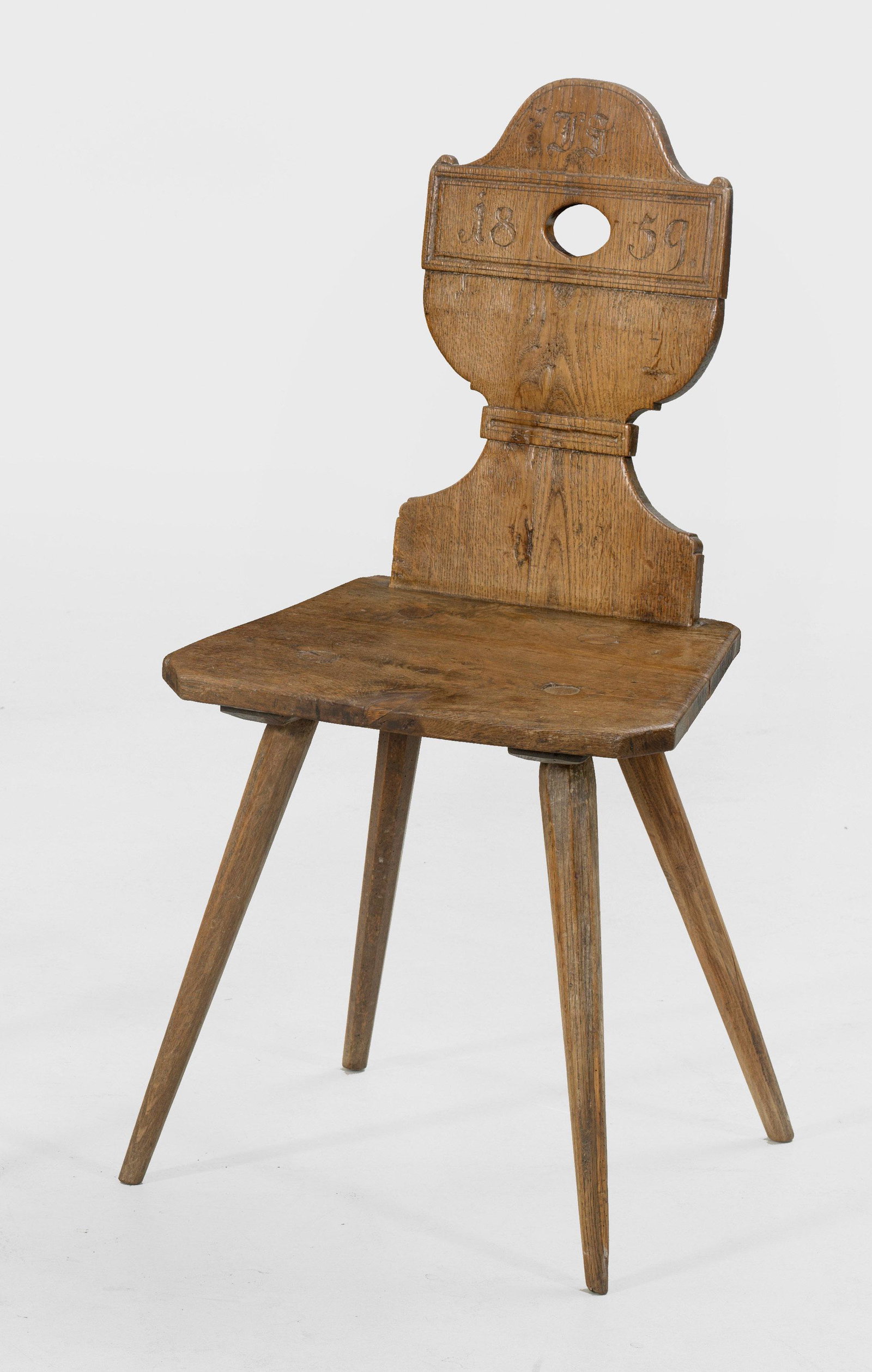 Biedermeier-Brettstuhl: Eichenholz. Flache trapezförmige Sitzfläche auf schräggestellten, spitz zulaufenden, gekanteten Beinen. Balusterförmige, durchbrochen gearbeitete Rückenlehne in Form einer gro