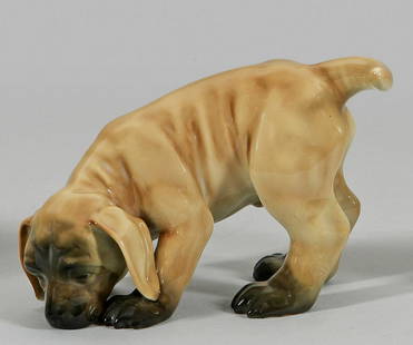 Schn&#252;ffelnder Hundewelpe: Schn&#252;ffelnder Hundewelpe Polychrome Unterglasurmalerei in Braun- sowie gr&#252;nschwarzen T&#246;nen. Entw. wohl Waldemar Lindstr&#246;m. Manufakturmarke. H. 12,5 cm. An early 20th C. porcelain f