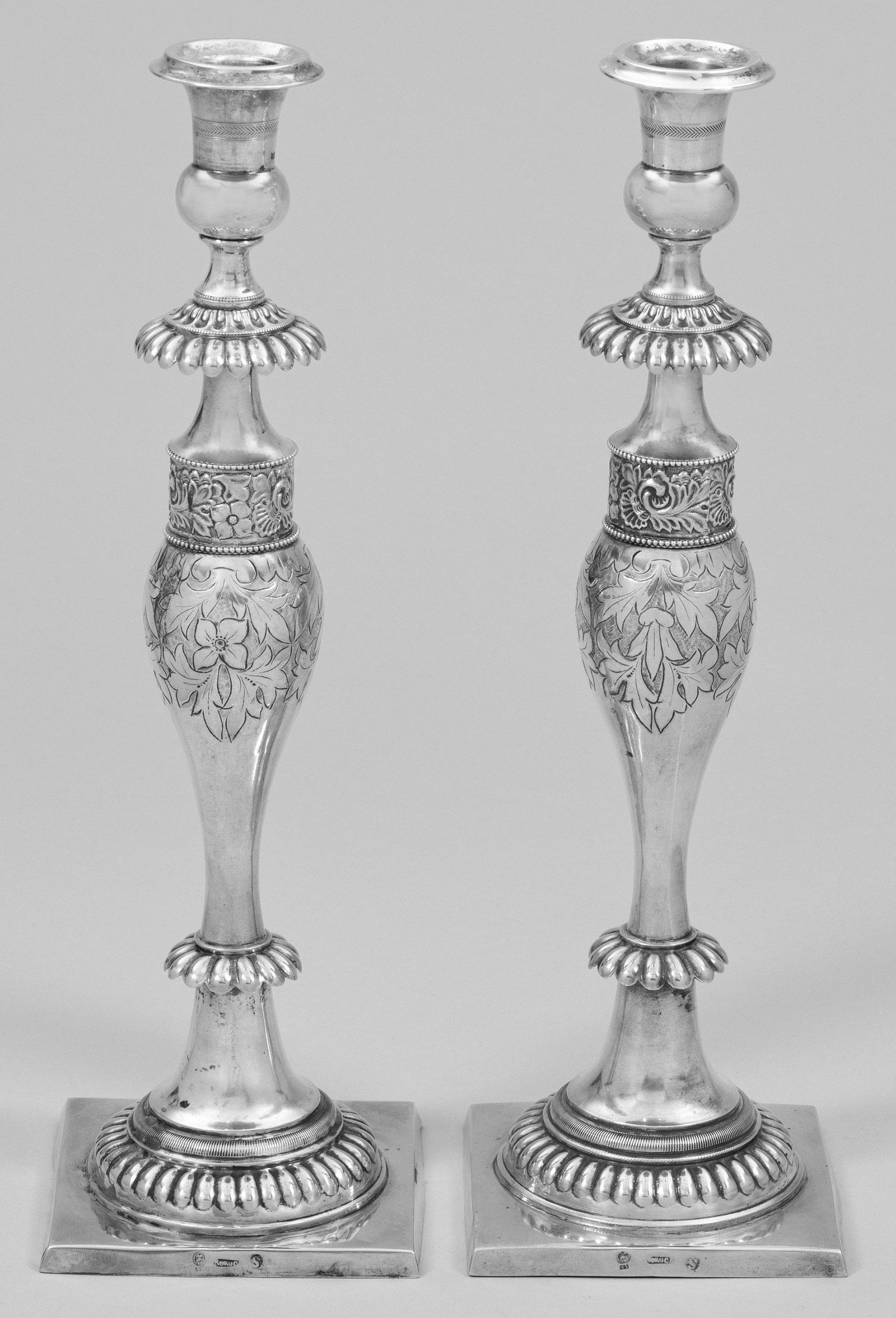 Paar groÃŸe Biedermeier-Tafelleuchter: Silber. Auf quadratischer Plinthe trompetenfÃ¶rmig hochgezogener, godronierter RundfuÃŸ. Ovoider, in einem stilisierten Blattfries endender, floral gravierter Balusterschaft von go