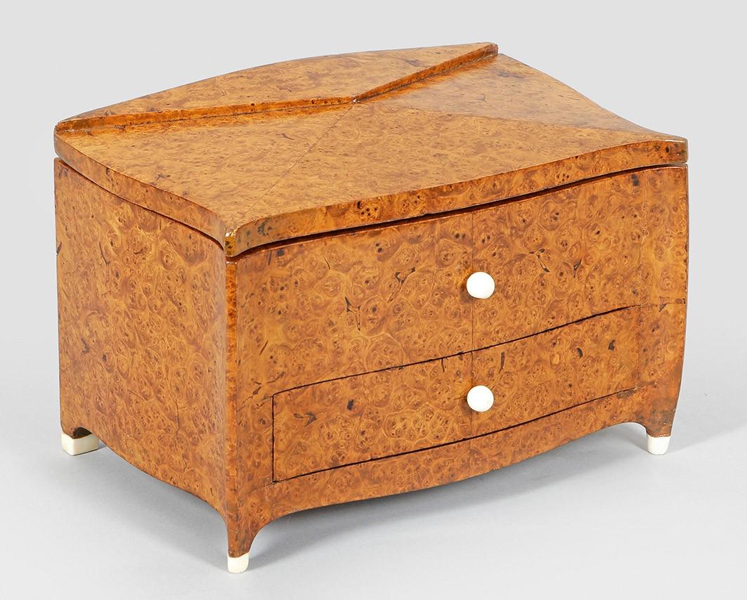 Art DÃ©co-Modellkommode: wohl nach einem Entwurf von Alfred Porteneuve Amboinamaser, furniert sowie Bein. Dreiseitig geschweifter, querrechteckig angelegter Korpus, flankiert von schlanken, leicht ausgebogten Ecklisenen, in n