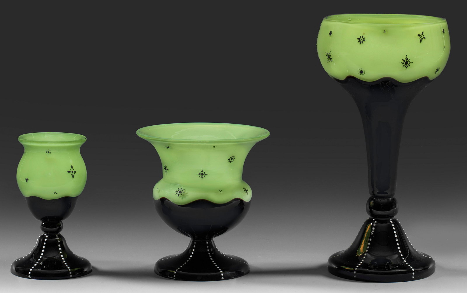 Drei Vasen von Loetz: Kelch- bzw. Krater- und Pokalform. Dekor in "Tango-Farben" aus hellgrünem, farblos überfangenem Opal- und schwarzem Glas; "Ausführung 165" bzw. "170" mit gestreuten, einzelnen Ornamentm
