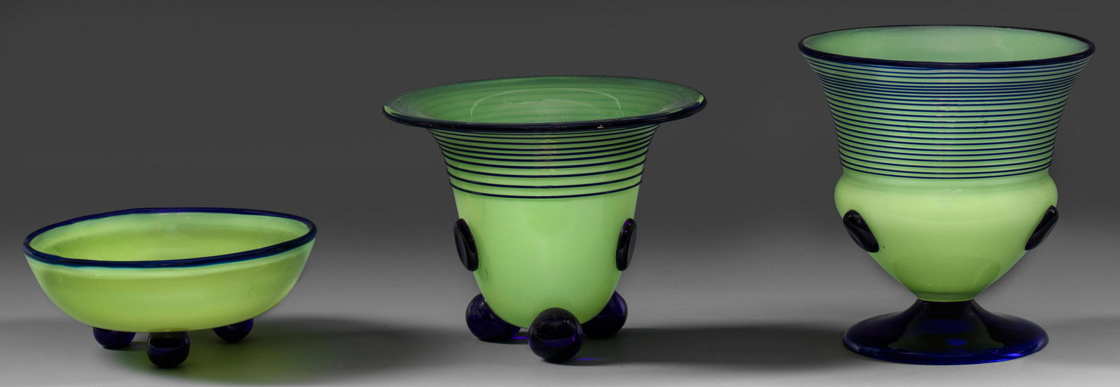 Zwei Vasen und eine kleine Schale von Loetz: Die Vasen in unterschiedlichen Glockenformen auf leicht gewölbtem Scheibenfuß bzw. drei Kugelfüßen, die gemuldete, runde Schale ebenfalls auf drei Kugelfüßen. In sog. "Ta