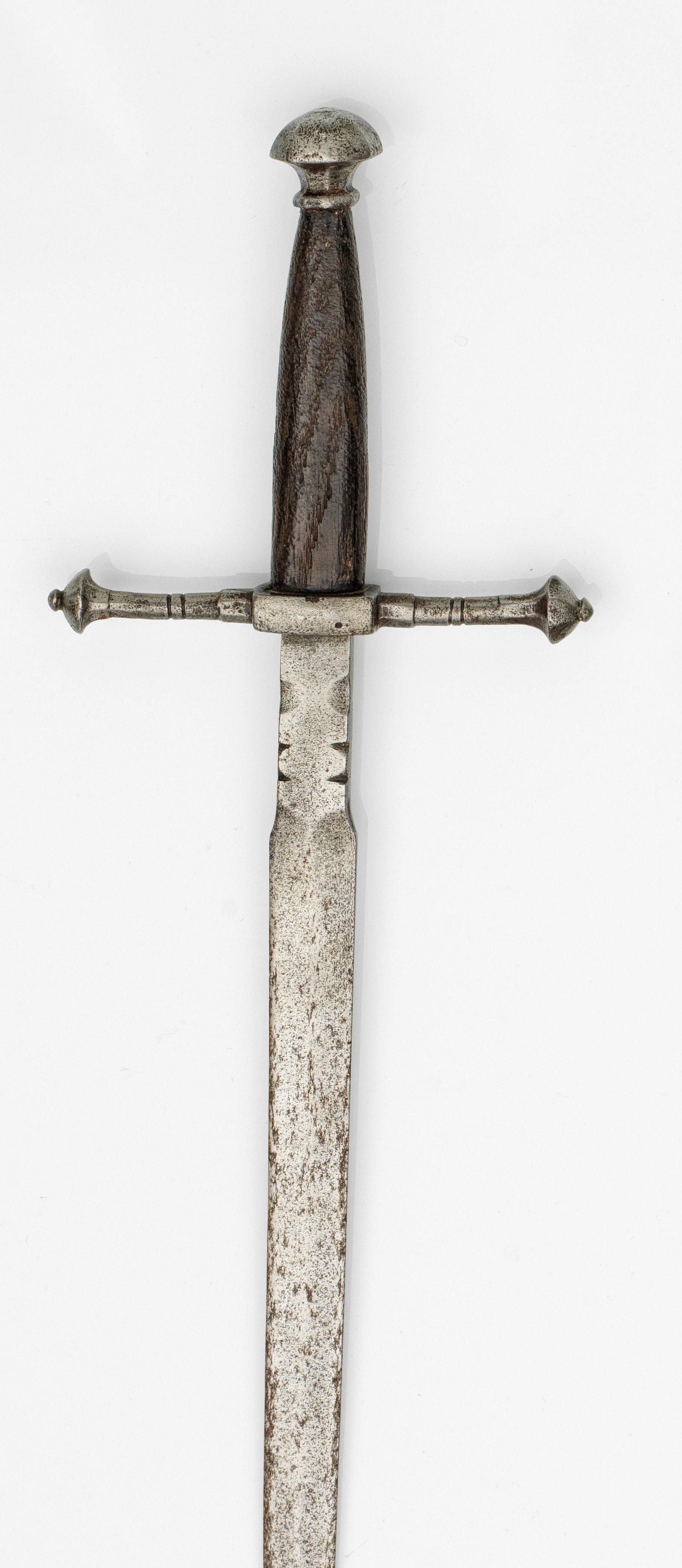 Linkhanddolch: Schlanke, zweischneidige und spitz zulaufende Klinge mit abgeflachtem Mittelgrat und kräftiger, gekehlter Fehlschärfe. Gerade Parierstange mit balusterknaufförmigen, facettierten Abschl