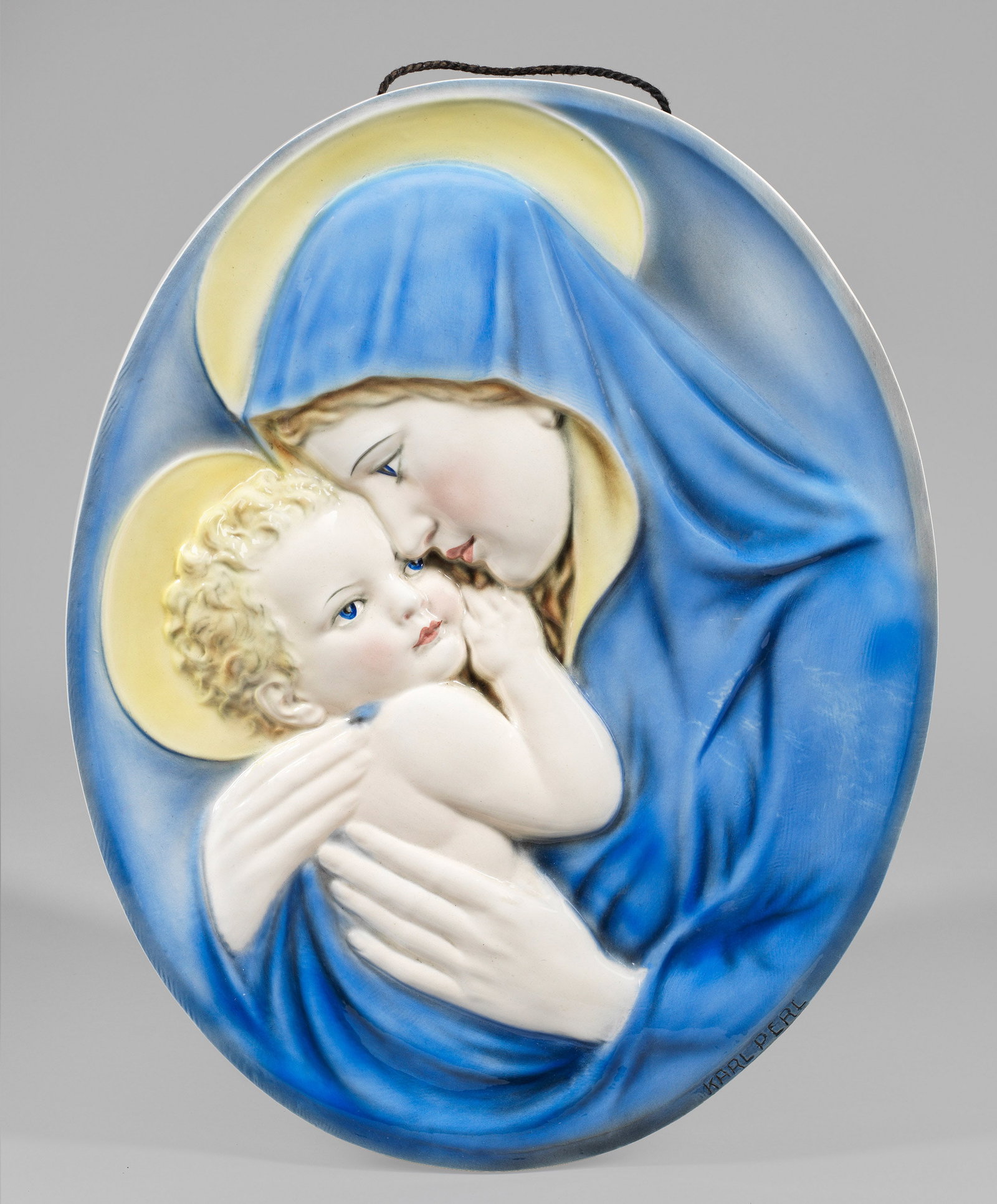 Madonnen-Wandrelief von Karl Perl für Keramos: Steingut, polychrome Unterglasurbemalung. Ovales Relief, oberhalb zwei originale Aufhängelöcher. Entw. Karl Perl, bez. "KARL PERL"; dreieckige Firmenmarke mit Bez. "MADE IN AUSTRIA". Ca. 49,