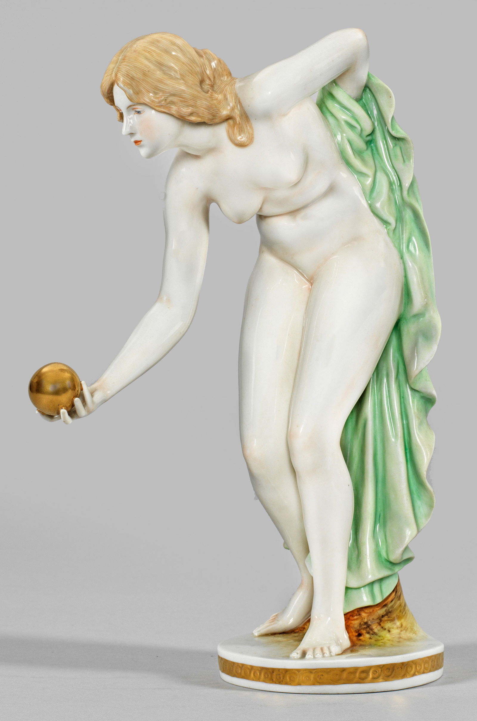 Kugelspielerin: Nach Meissener Vorbild von Walter Schott. Auf goldstaffierter, runder Plinthe mit Flechtbandbordüre, unbekleidet stehendes, sich vorbeugendes Mädchen in ihrer rechten Hand eine goldene Kugel