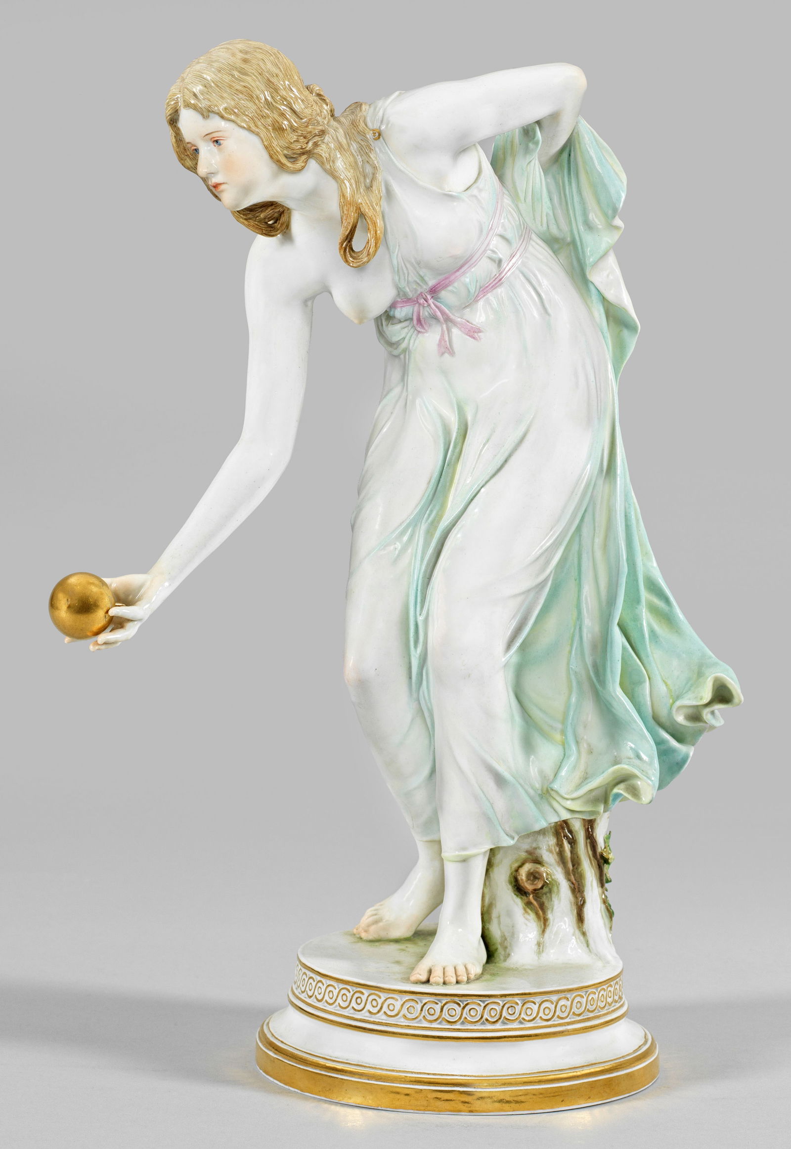 Jugendstil-Figur "Kugelspielerin" von Walter Schott: Auf rundem, profiliertem Sockel mit Flechtbandbordüre stehendes, sich vorbeugendes Mädchen in einem hauchdünnen, den Körper umschmeichelndem, mintgrün staffiertem Kleid, in ih