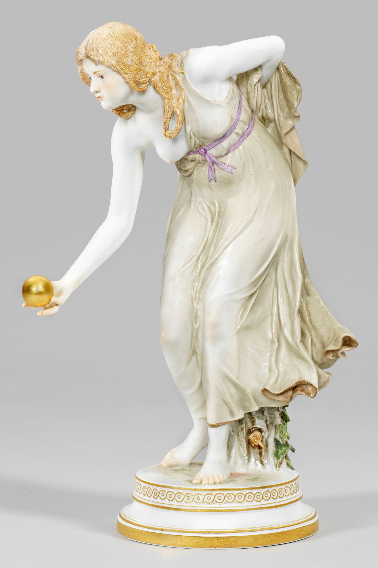 Jugendstil-Figur "Kugelspielerin" von Walter Schott: Runder profilierter Sockel mit Flechtbandbordüre. Stehendes, sich vorbeugendes Mädchen in einem hauchdünnen, bräunlich staffierten Kleid, in ihrer rechten Hand eine goldene Kugel z