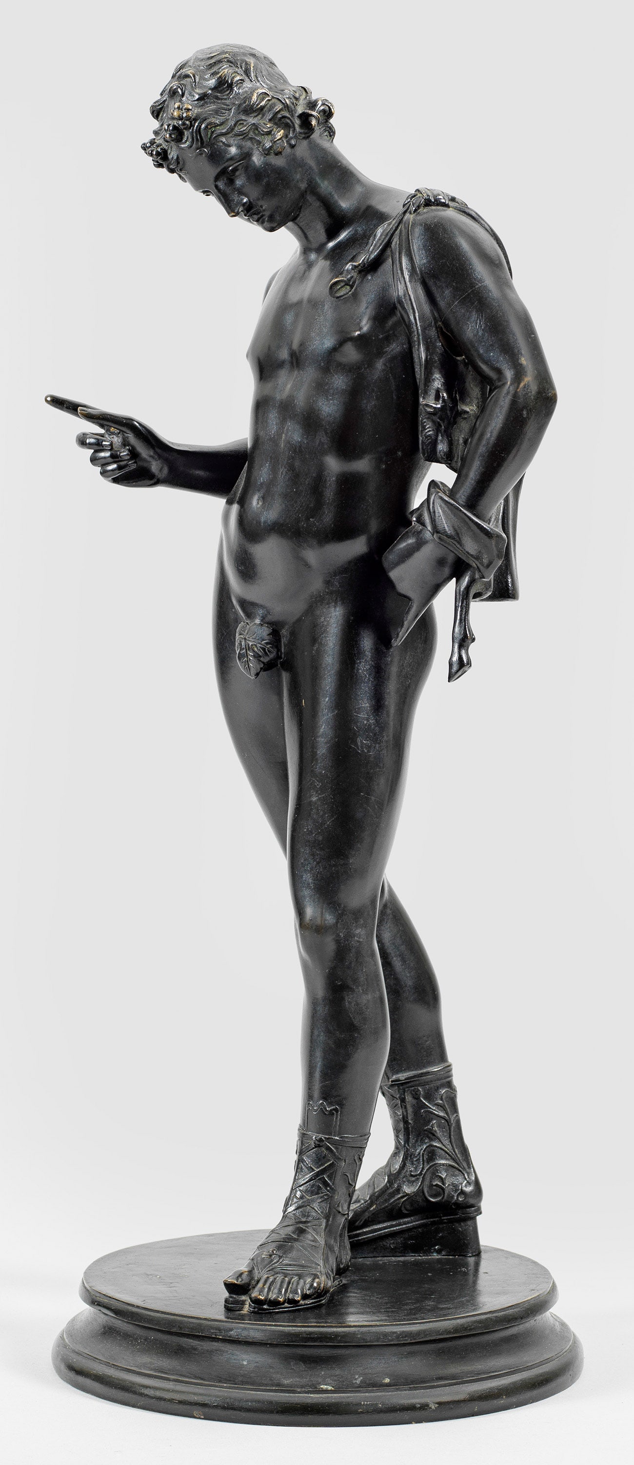 Dionysos: sog. Narziss von Pompeji Bronze, dunkel patiniert. Auf rundem, gekehltem Sockel stehender, männlicher Akt mit Ziegenfell über der Schulter und erhobenem Zeigefinger. Nach der 1862 in Pompeji