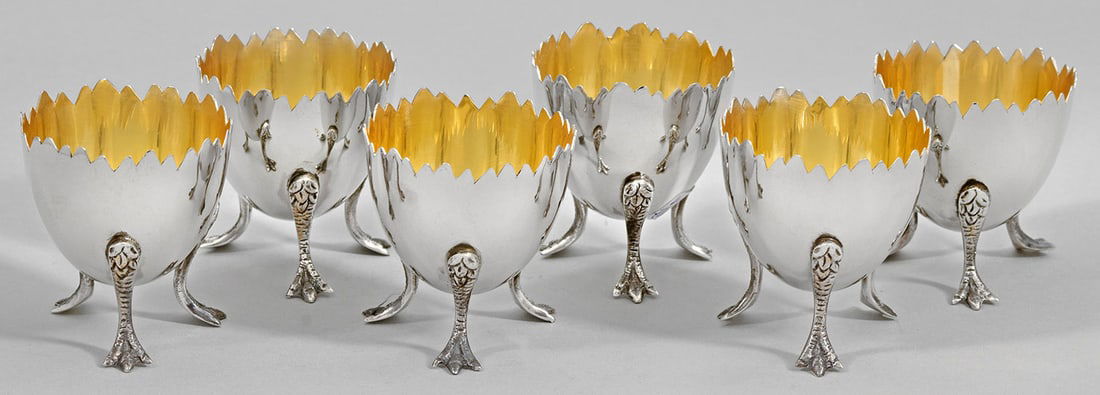 Satz von sechs Eierbechern: Sterlingsilber. Dekorativ in Form eines aufgebrochenen Eies gestalteter Korpus auf stilisierten Krallenfüßen. Innen vergoldet. Gest. 925. Gew. zus. ca. 290 g. H. 5,7 cm. A set of six decorative Ster