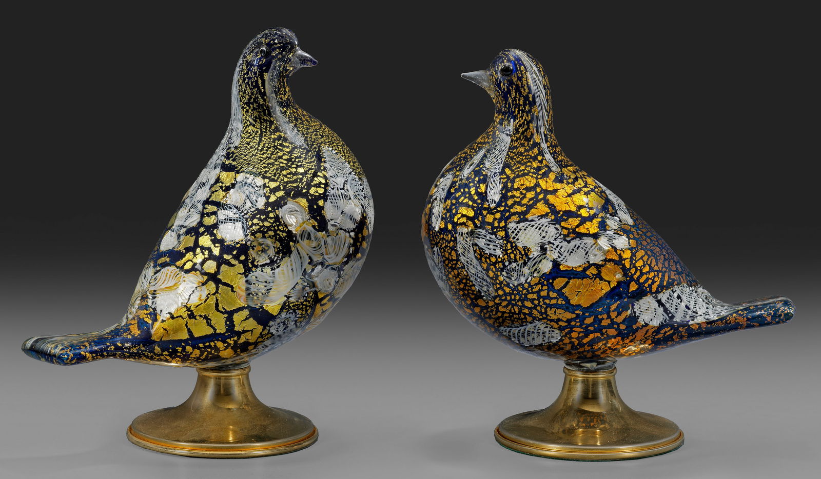 Taubenpaar von Aldo Nason: Gegenstücke. Stilisierte Tauben aus Überfangglas (farblos und dunkelblau) mit Metallfolieneinschlüssen (Gold und Platin) sowie eingeschmolzenen Zanfirico-Stücken. Schnäbel aus farblosem Glas, Aug