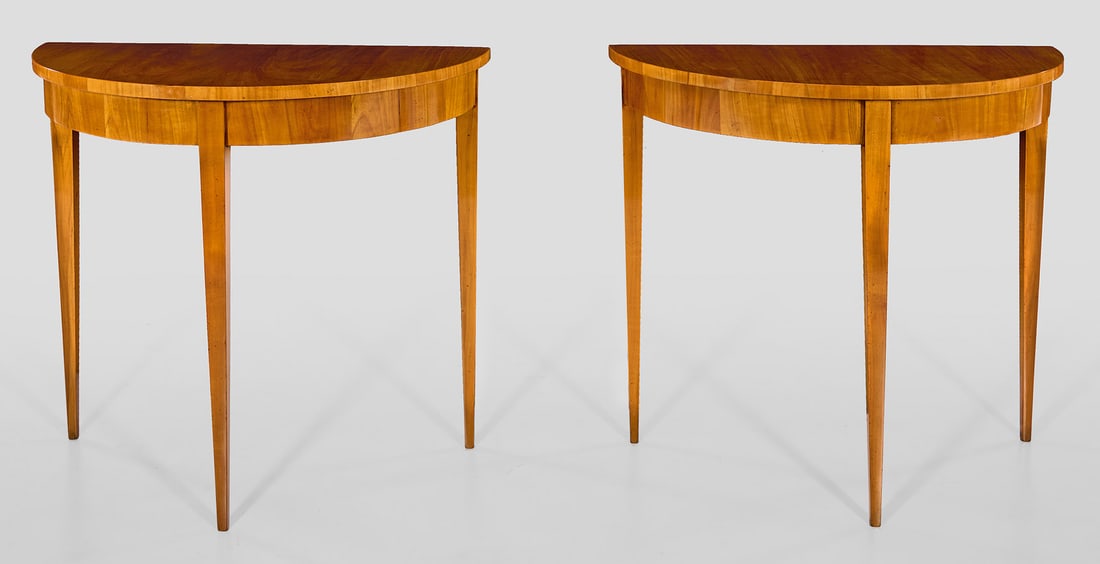 Paar Demilune-Konsoltische: Kirschbaum, furniert. Bombierte Zarge auf hohen, konischen Vierkantbeinen. Gering überstehende Deckplatte. H. 75 cm. 80 cm x 40,5 cm. A pair of South German cherrywood veneered console tables. Südde