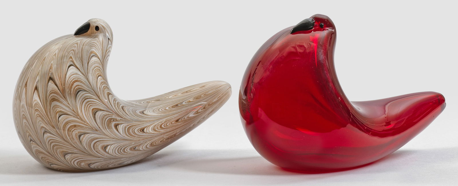 Paar "Neolitico"-Tauben von Barovier & Toso: Farbloses bzw. rubinrotes Glas, teilw. spiralartige Bandeinschmelzungen aus weißen und ockerbraunen gekämmten Glasmassen. Entw. Ercole Barovier, 1954 für Barovier & Toso. H. 13 cm. L. 19 cm. Proven