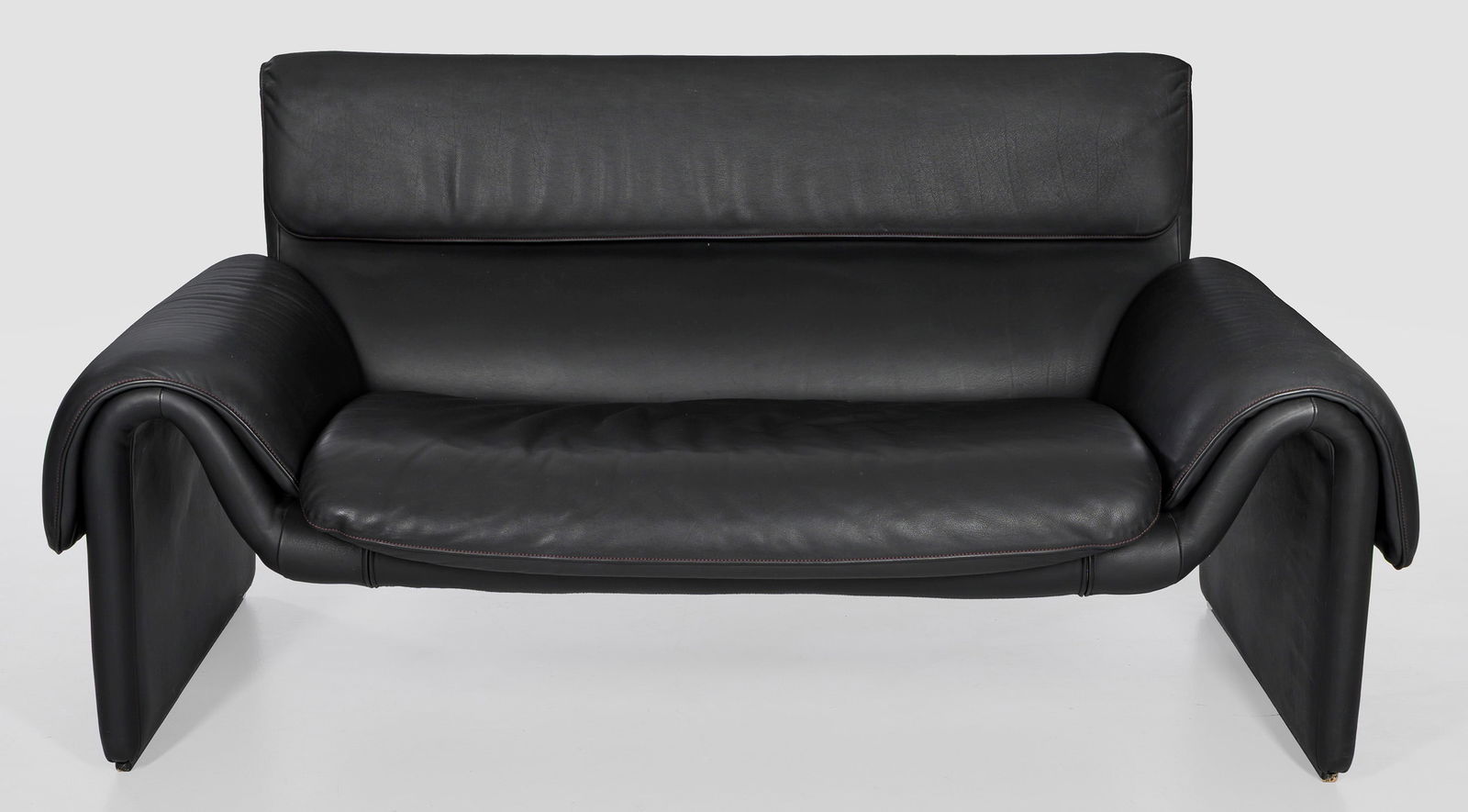 Designer Sofa "DS 2011" von De Sede: Schwarzes Leder. Korpus aus flachen, stark gebogten Wangen, in Armlehnen und Sitzfläche übergehend. Rechteckige Rückenlehnenrahmung. Herstellerzeichen. Entw. 1983. H. 82 cm. 165 cm x 70 cm. Sitz-H.