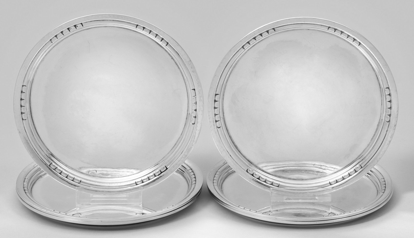 Satz von sechs Georg Jensen-Untersetzern: Silber. Flacher Spiegel mit Hammerschlagdekor und schmaler, profilierter Rand, teilw. umzogen von Perlfries. Gest. 830, Herstellerzeichen. Ges.-Gew. ca. 920 g. D. 17 cm. A set of six Georg Jensen silv