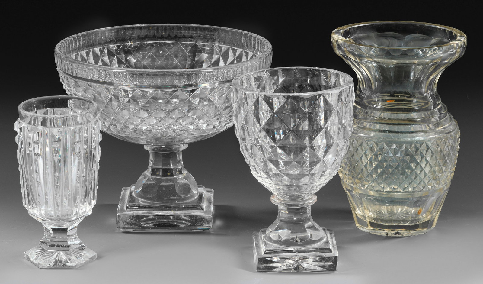Zwei Fußschalen und zwei Vasen im Biedermeierstil: Farbloses, teils rauchstichiges Glas mit Steinel-, Schäl-, Kerb- und Olivenschliff. H. 16 cm - 20,5 cm. D. maximal 22,5 cm. A group of four 19th century cut glass vases and footed bowls. Deutsch/Böh
