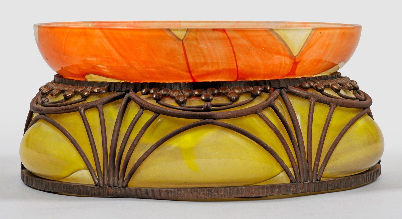 Große Art Déco-Schale mit Metallmontierung von André Delatte: Runde, gebauchte, sechsfach gebuckelte Form mit hochgezogenem, weitem Rand. Überfangglas, farblos sowie orangefarben, gelb und opaleszierend marmoriert; geblasen in eine ornamental stilisierte Metall