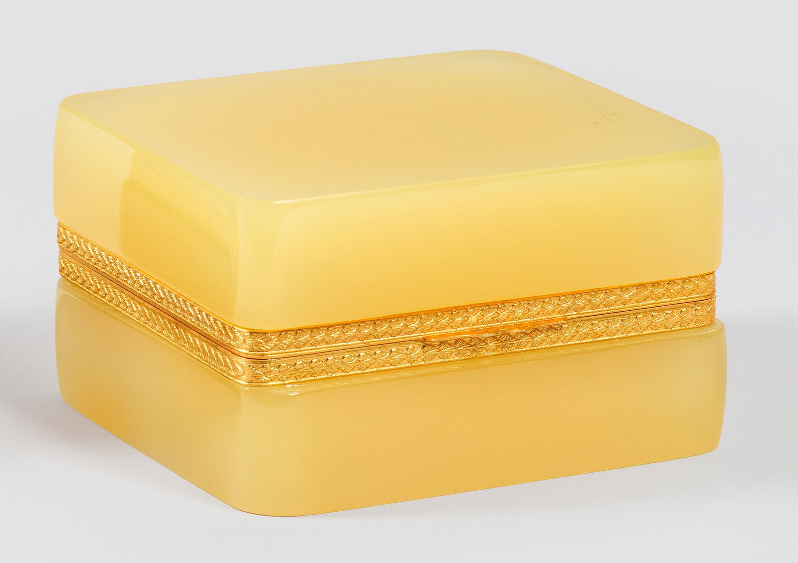 Art Déco-Zierdose: Rechteckige Form mit abgerundeten Ecken. Sandfarbenes, opakes Uran-Glas, geschliffen und poliert. Scharnierte, reliefierte Messingmontierung. H. 7,3 cm, 12,5 cm x 10,8 cm. A French Art Deco sand-colou