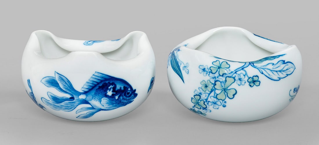 Paar Handschalen "Zierfische" und "Blaue Hortensie".: Originaltitel Oval gewölbter, dreipassig eingeschnürter Korpus mit hoch gerundeten Ecken. Umlaufend der Wandung zwischen Pflanzen schwimmende Fische bzw. Blüten in blauer, teilw. pastelltoniger Unt