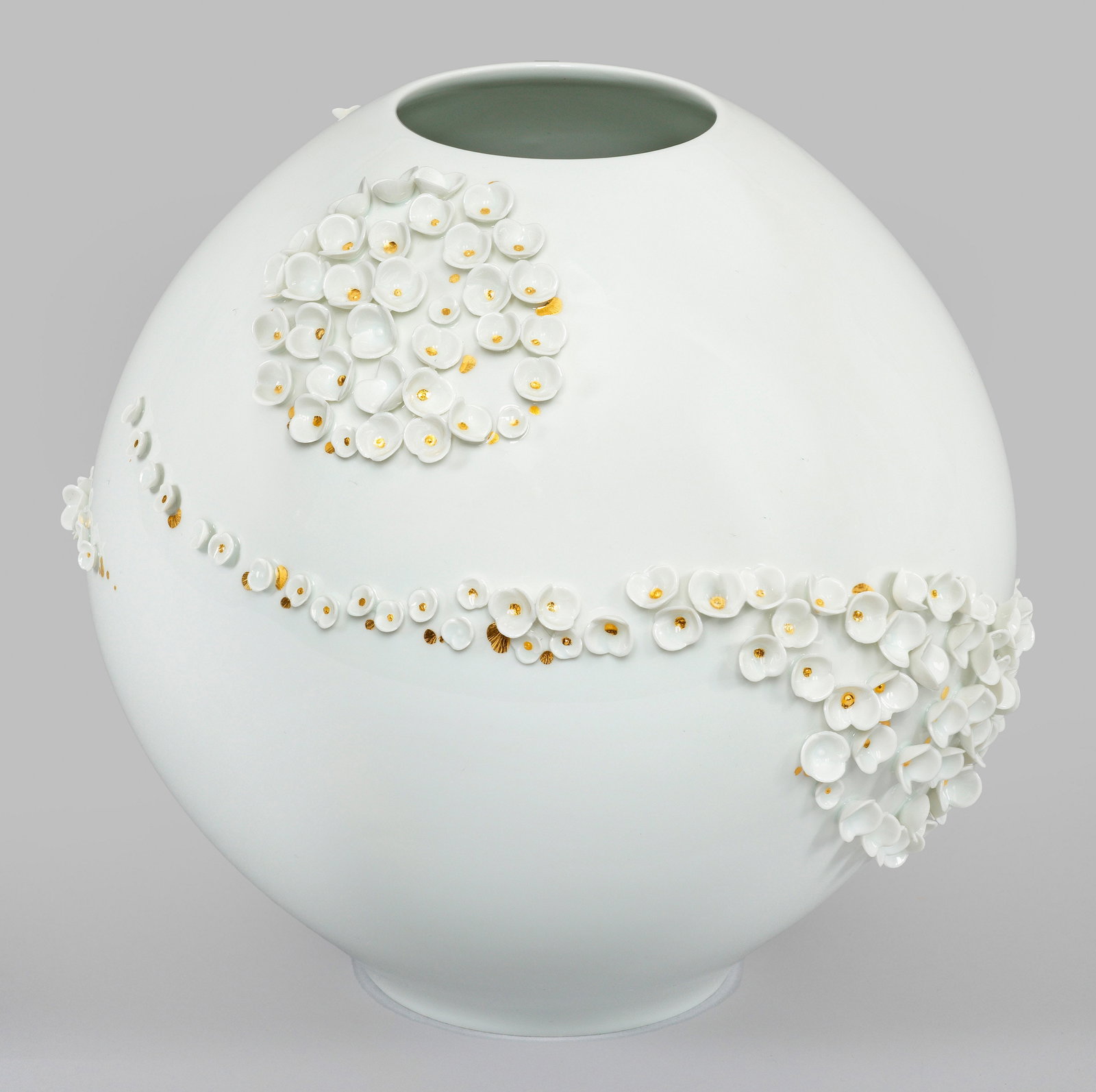Vase "Blütenkomposition". Originaltitel: Weißporzellan. Über dem Rundstand kugelig gewölbter, sich oberhalb verjüngender Korpus. Auf der Wandung aufgelegter Blütenbelag in Anlehnung der Schneeballenblüten von J. J. Kaendler. Goldstaffa