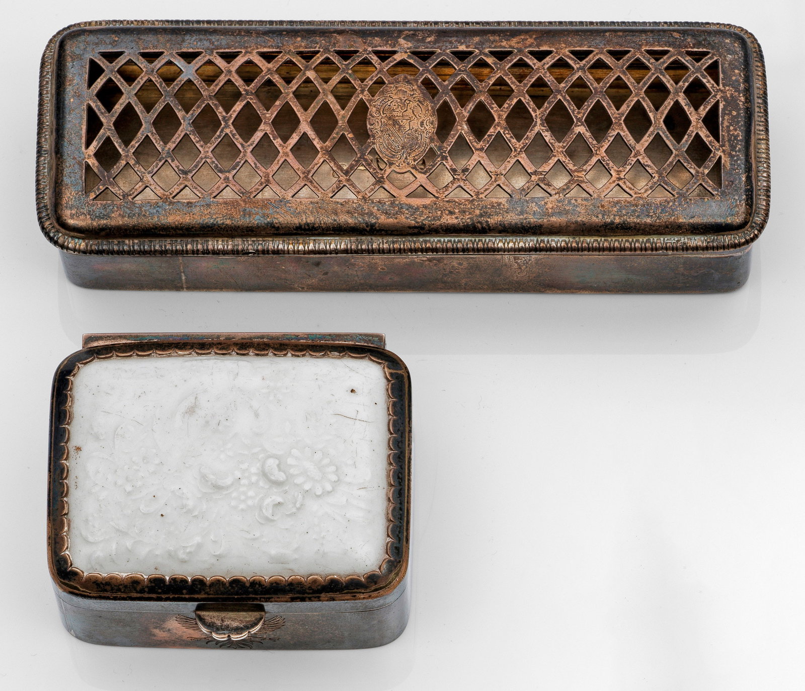 Zwei Tabatieren: Silber, Porzellan. Rechteckiger Korpus mit scharniertem, leicht aufgewölbtem Deckel. Deckel durchbrochen gearbeitet mit mittiger Wappenkartusche bzw. aus Porzellan mit Blumendekor und polychrom gemal