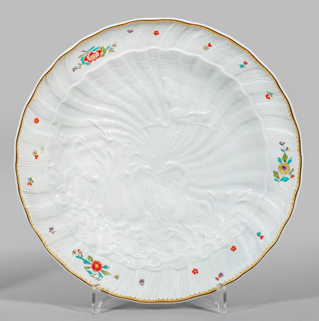 Große Anbietschale mit Schwanenservice-Dekor: Runde, gemuldete Form. Im Spiegel feiner, muschelförmiger Reliefdekor mit zwei einander zugeneigten Schwänen sowie fliegendem und zwischen hohem Schilf stehendem Reiher mit Indianischem Blütendekor