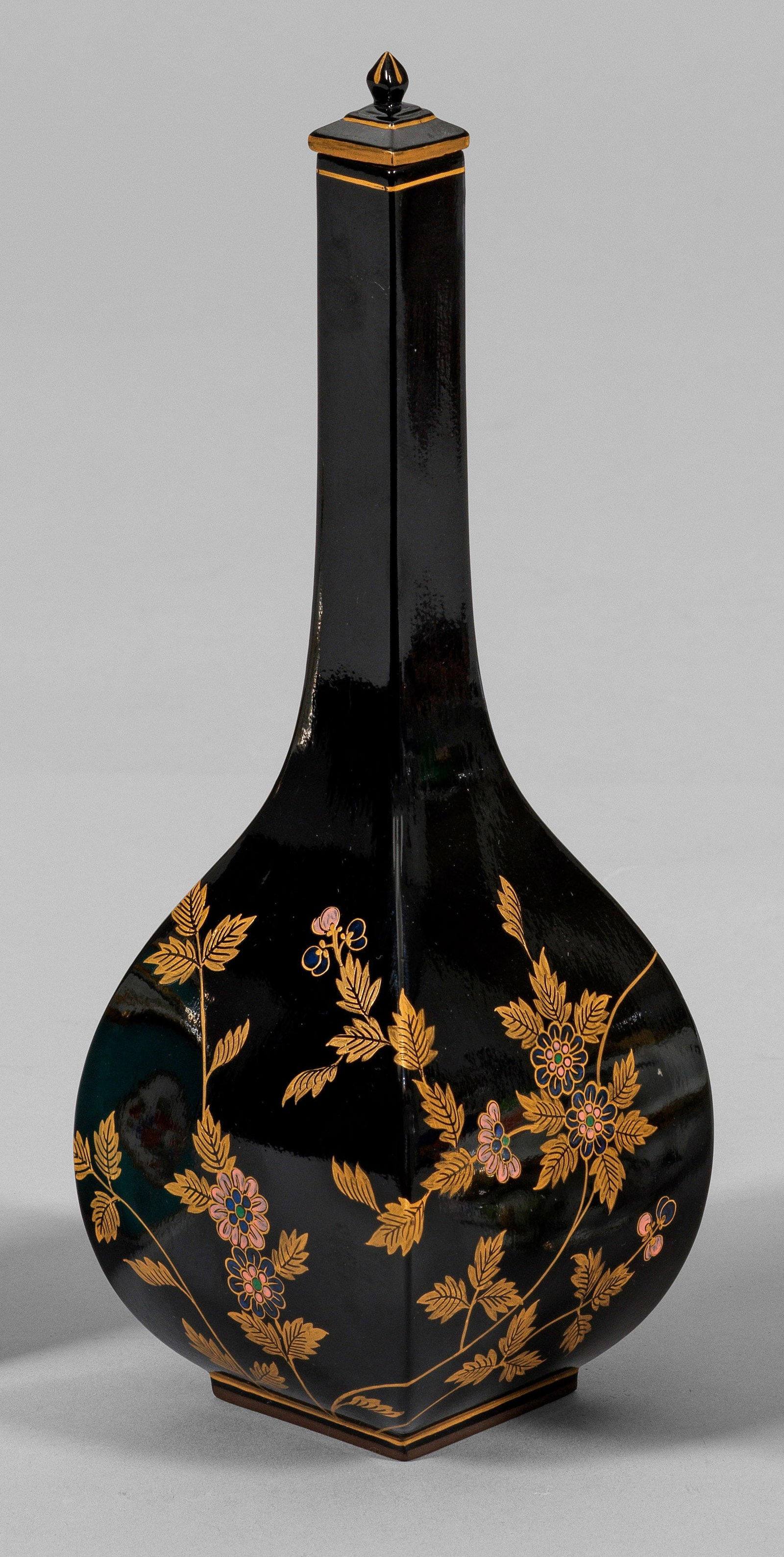 Sakeflasche mit Gold- und Lackmalerei: Böttgersteinzeug, schwarz glasiert. Über einem quadratischen Stand vierkantiger, in langen, schmalen Hals übergehender Korpus. Passiger, gestufter Deckel mit spitz zulaufendem Knauf. Umlaufend auf