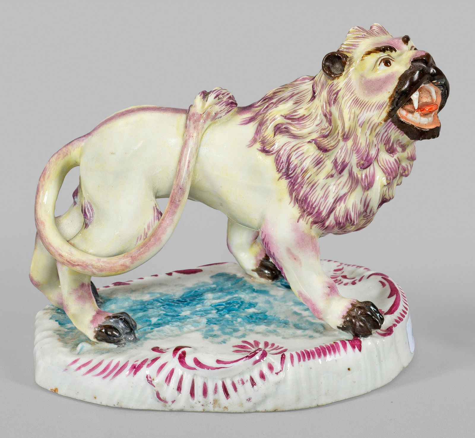 Kleine Löwenfigur: Fayence, sandfarbener Scherben. Auf einem ovalen, rocaillereliefierten Sockel stehender, brüllender Löwe. Bemalung in polychromer Muffelmalerei. Rest.; Etikett der Sammlung R. G. Vater mit Nr. 573.
