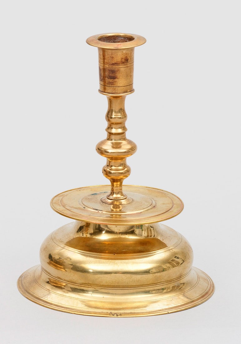 Glockenfußleuchter: Messing. Gegossener, sehr dünn abgedrehter Nürnberger Barockleuchter. Nach oben durch einen breiten Teller abgeschlossener Sockel mit starker Auswölbung und flachem Rand, Balusterschaft mit einer f