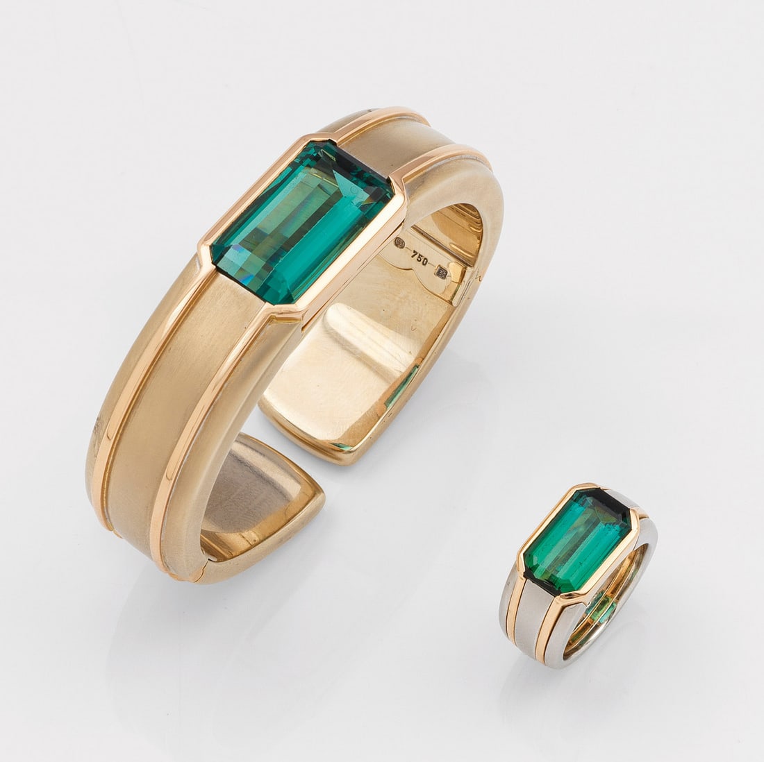 Demi Parure mit Turmalinen von Gebrüder Hemmerle, München: Anfang der 1990er Jahre Bicolor, Platin und Gelbgold, gest. 750/PLT. Profilierte, satinierte Bandform, zentral besetzt mit jeweils einem petrolgrünen Turmalin von 21 ct. bzw. 6 ct., im Baguetteschlif