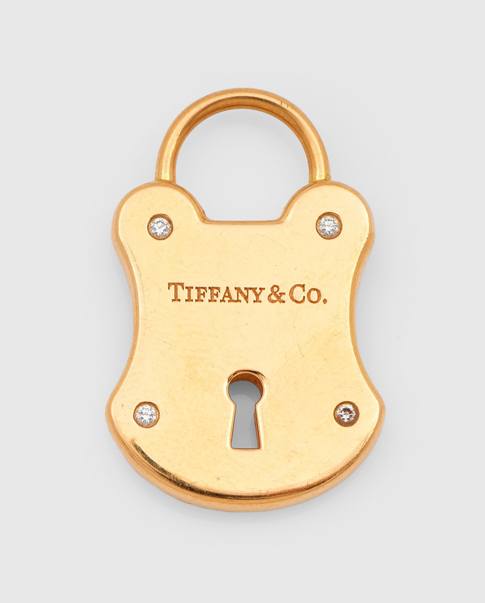 Schloß-Anhänger mit Brillanten von Tiffany & Co.: Roségold, gest. 750. Plastisch gestaltetes Schloß, besetzt mit vier kleinen Brillanten. Herstellerzeichen. Original Beutel. Gew. ca. 12,55 g. Lock pendant by Tiffany & Co., set with small diamonds,